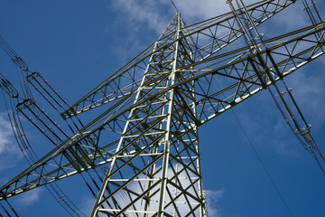 A German electricity pylon stands against a clear blue sky, showing the power transmission network. The steel mast supports the electric grid and the energy transition. © René Notenbomer