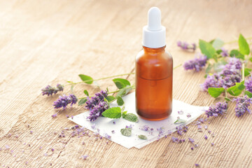 Patchouli essential oil or extract in glass bottle dropper with flowers on wooden table, closeup, natural medicine and healthy skin and body treatment concept
