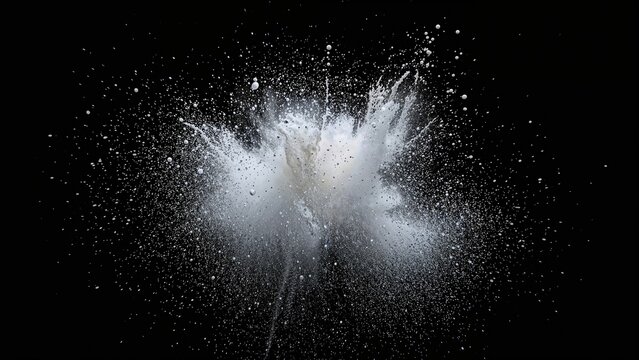 Explosion of white powder or dust with particles dispersing in black background.