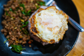Thai crispy fried egg on rice and stir fried beef with holy basil