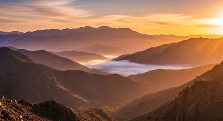 Obraz premium Sunrise over the mountain range with fog in the valley creating a scenic view