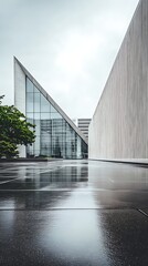 Obraz premium Modern architecture with triangular glass facade and reflection on wet surface after rain