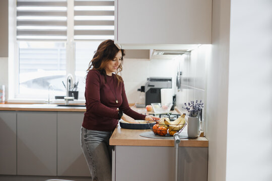 Woman preparing meal in modern kitchen with vegetables on wooden countertop, healthy cooking and food preparation at home. healthy lifestyle concept