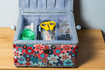 Open colourful sewing box with scissors, needles and a measuring tape.  Needlecraft or hobby concept