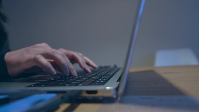 Close-up of hands typing on laptop keyboard in low light, symbolizing freelance work, late night productivity, remote job, digital workspace, or focused technology usage in a modern setting.

