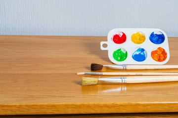 Wooden handled paint brushes and a watercolour palette with colourful paint with copy space for text, arts, hobbies and leisure concept