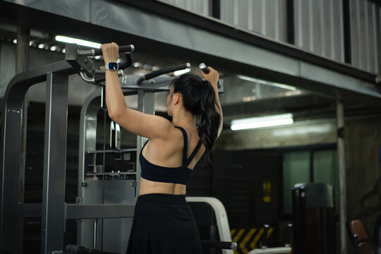 Woman training back on a pull-up machine in a gym, showing strength, focus, and an active lifestyle. - Powered by Adobe