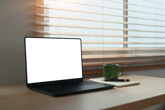 Blank screen laptop computer on table at home office with coffee and notepad, pen - Powered by Adobe