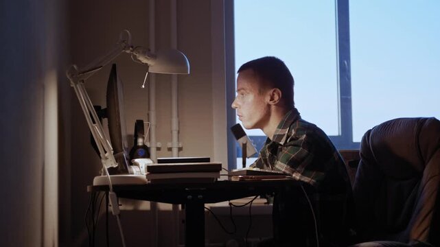 Man with undeveloped arms works late at his computer, demonstrating accessibility and inclusion in modern work environments.