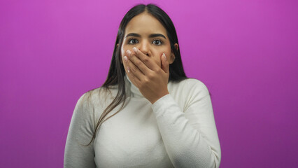 Woman surprised with hand over mouth against a vibrant pink background showcasing emotion and expression in an isolated studio setting.