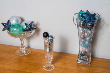 Three different shaped vases with blue metallic baubles on a wooden cabinet