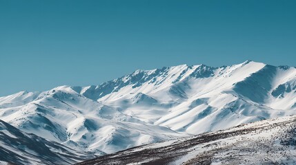 Majestic snow covered mountain range stretches across the horizon under a clear blue sky