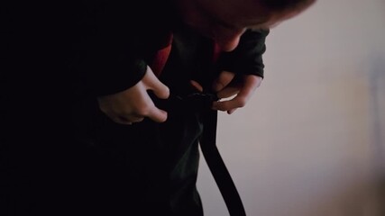 A determined disabled man secures his backpack on his chest in the morning sun before stepping outside to begin his day.