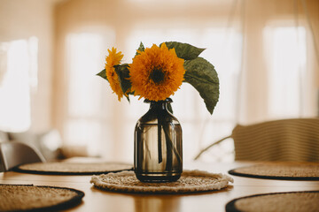 Black vase with sunflowers on the table.