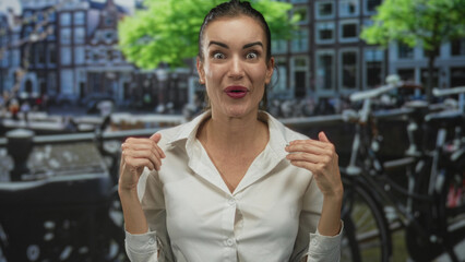 Hispanic woman folds hands under chin and shows intense expression on a street with bicycles by...