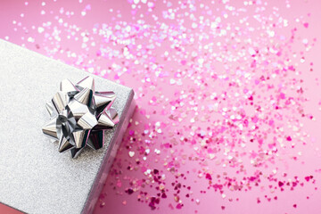 Silver gift box and decorations on pink background.
