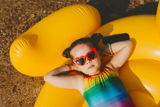 Little girl with heart shaped sunglasses sunbathing on the beach.