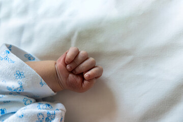 Newborn baby hand in a tiny fist sleeping