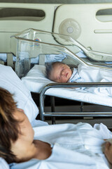New mother looking at sleeping newborn baby in hospital