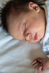 Newborn baby sleeping peacefully on white bed
