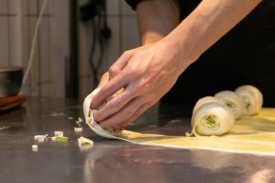 Chef hands rolled pastry dough on stainless table preparing (Guo Kui), crispy stuffed flatbread is truly scrumptious with flaky and crispy layers. Chengdu street food, China.