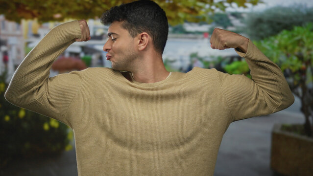 Man muscle flex outdoor hispanic young guy fitness strength pose displays confidence.