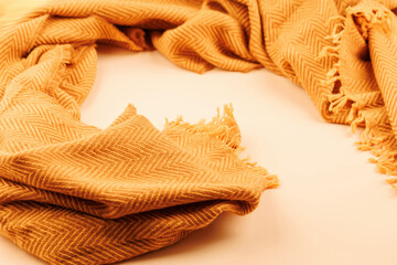 Mustard yellow wool scarf with herringbone pattern and fringed edges on beige background