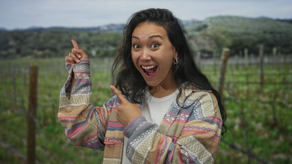 Naklejka premium Woman points finger with open mouth in forest wearing patterned jacket and hoop earring; excitement.