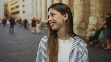 Fototapeta premium Woman turns head to side showing bright smile on street near historic building; travel exploration joy.