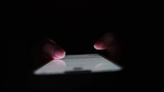 Dark Cybersecurity Scene with Hands Typing Anonymously on a Smartphone at Night. Suspicious digital activity suggesting hacking, online aggression, or hidden conversations.