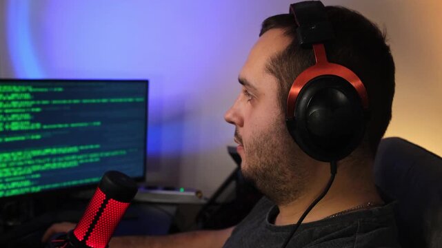 Focused Gamer Working , While Writing Code During Late Evening Hours. Intense atmosphere of concentration, illuminated by colorful lights and professional streaming gear.