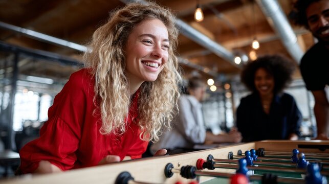 Group of people playing foosball in an office setting.