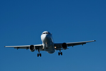 Airplane seconds before landing - low flight against clear blue sky.