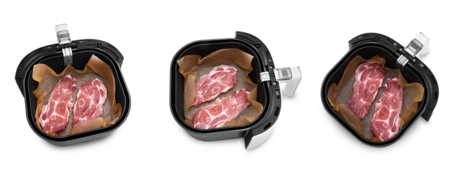 Raw pork neck slices placed in an air fryer basket lined with baking paper, isolated on a transparent background for cooking.