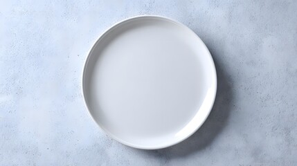 A top down view of a white round plate on a textured light background