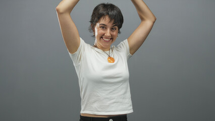 Woman raising arms overhead, looking upward and smiling while wearing a white tshirt and orange...