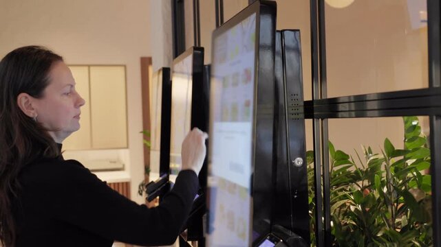 A woman uses a digital touchscreen menu at a cafe, selecting items and completing her order. Modern urban lifestyle and smart technology.