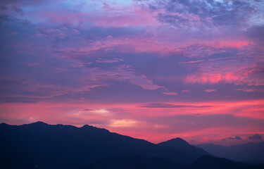 Mountains silhouette under beautiful bright sunset sky with colorful clouds. 