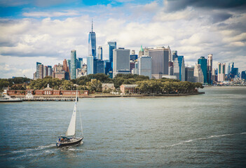 Sailboat glides across the Hudson River with the Lower Manhattan skyline and One World Trade Center in the background.