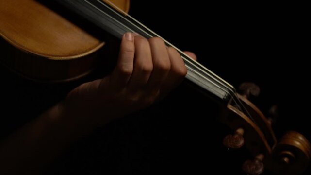 Musico tocando el violin sobre fondo negro, imagenes primer plano, detalles de violin estilo cinematografico