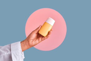 Hand holding yellow cosmetic product bottle