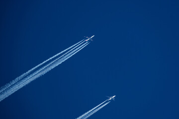 Airplanes in the blue sky. Contrails from two planes flying side by side