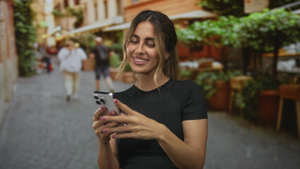 Woman holds smartphone with bare arms tapping screen on cobblestone alleyway; excitement victory celebration joy.