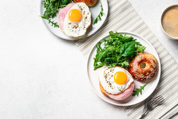 Healthy breakfast. Bagels with fried egg, ham and greens
