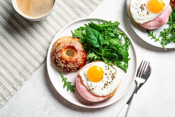 Healthy breakfast. Bagels with fried egg, ham and greens