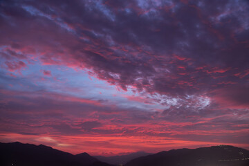 Mountains silhouette under beautiful bright sunset sky with colorful clouds. 