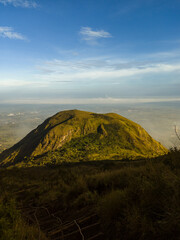 The view during a morning hike or sunrise on Mount Penanggungan is beautiful. It offers a vast landscape, including savannahs and ancient buildings like temples.