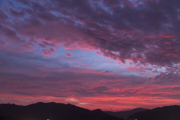 Mountains silhouette under beautiful bright sunset sky with colorful clouds. 