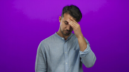 Young hispanic man looking frustrated over isolated purple background, capturing expressive gestures and emotions.