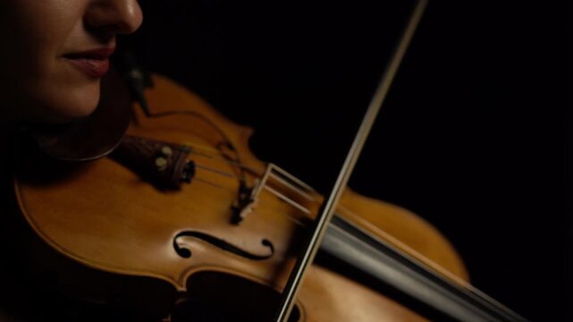 Musico tocando el violin sobre fondo negro, imagenes primer plano, detalles de violin estilo cinematografico